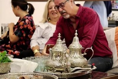 Two Moroccan Teapots On Tray In Front of Three Persons