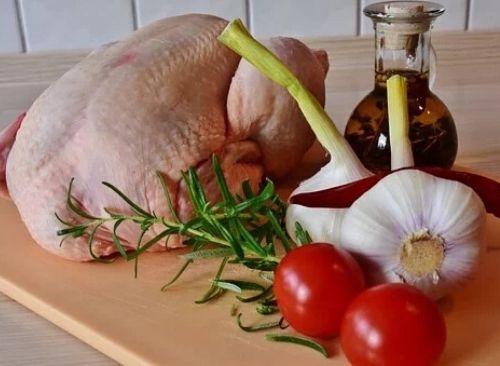 Raw Whole Chicken With Vegetables On Brown Cutting Board